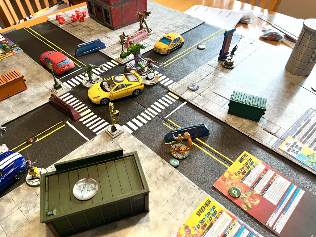 Several superhero models placed on a city street-themed board