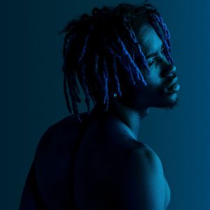 Black man posing by a blue background
