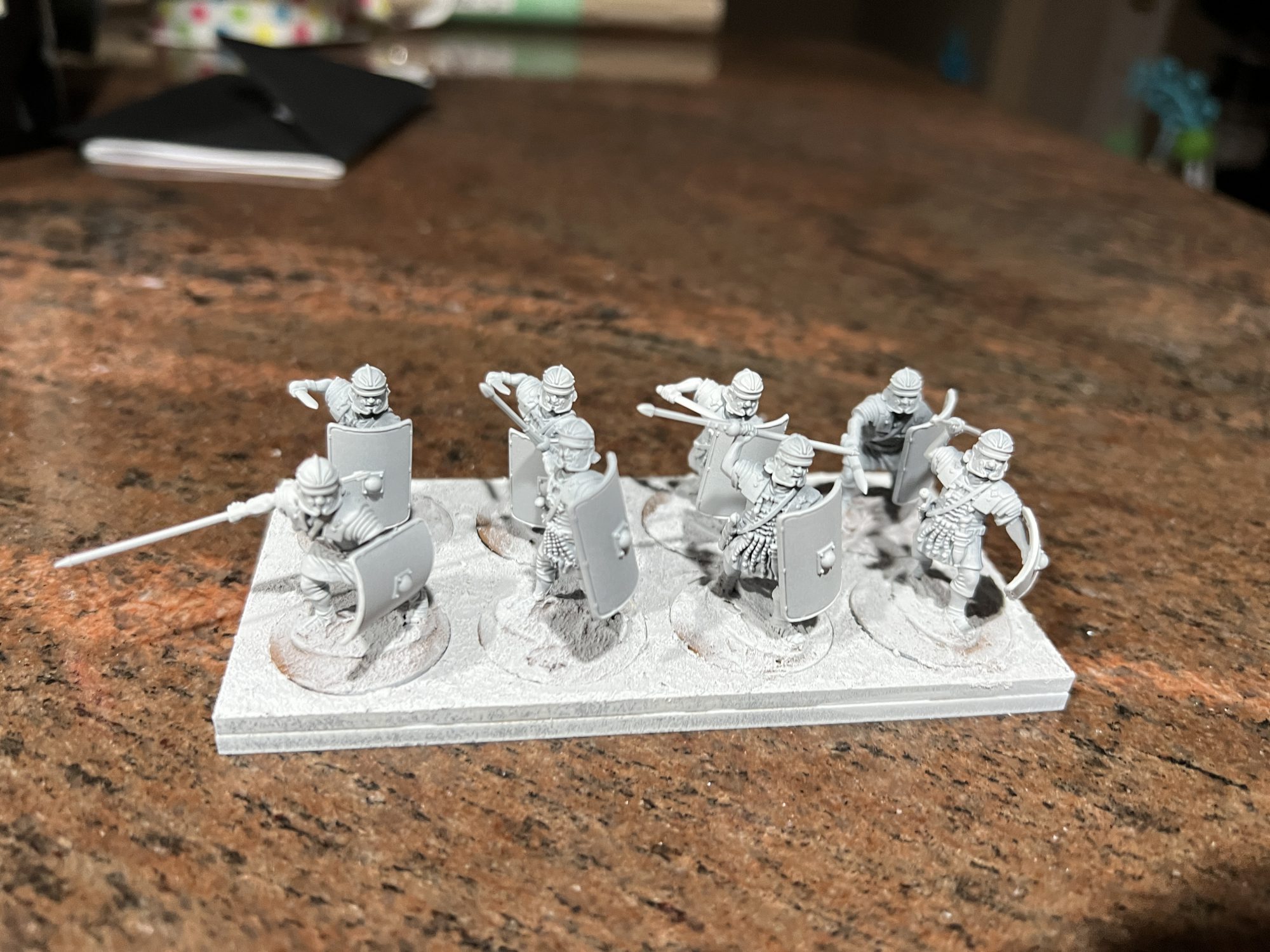 Eight miniature Roman legionnaires mounted on sabot bases primed white.