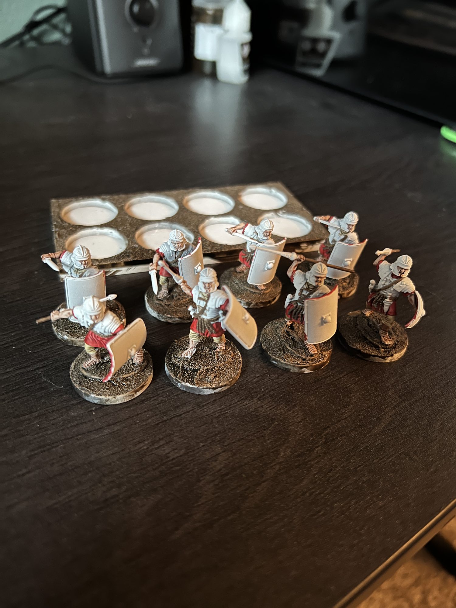 Eight miniature Roman Legionnaires mounted on circle bases in the process of being painted.