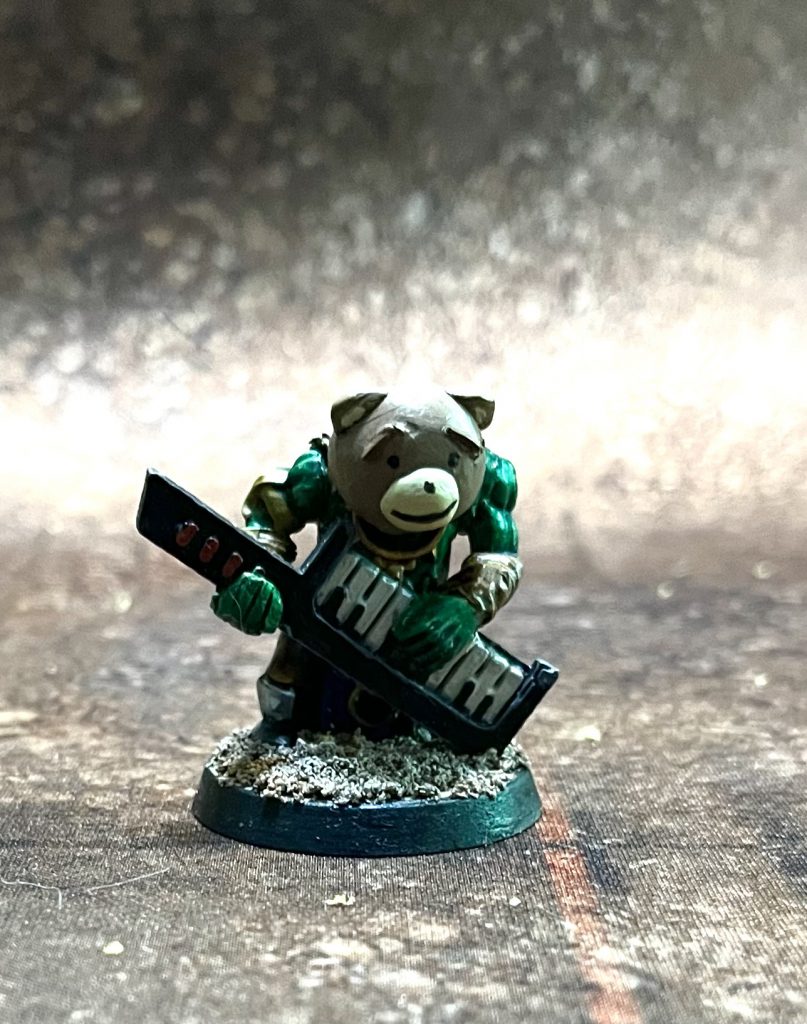 An ork wearing a costume bear head, playing a keytar.